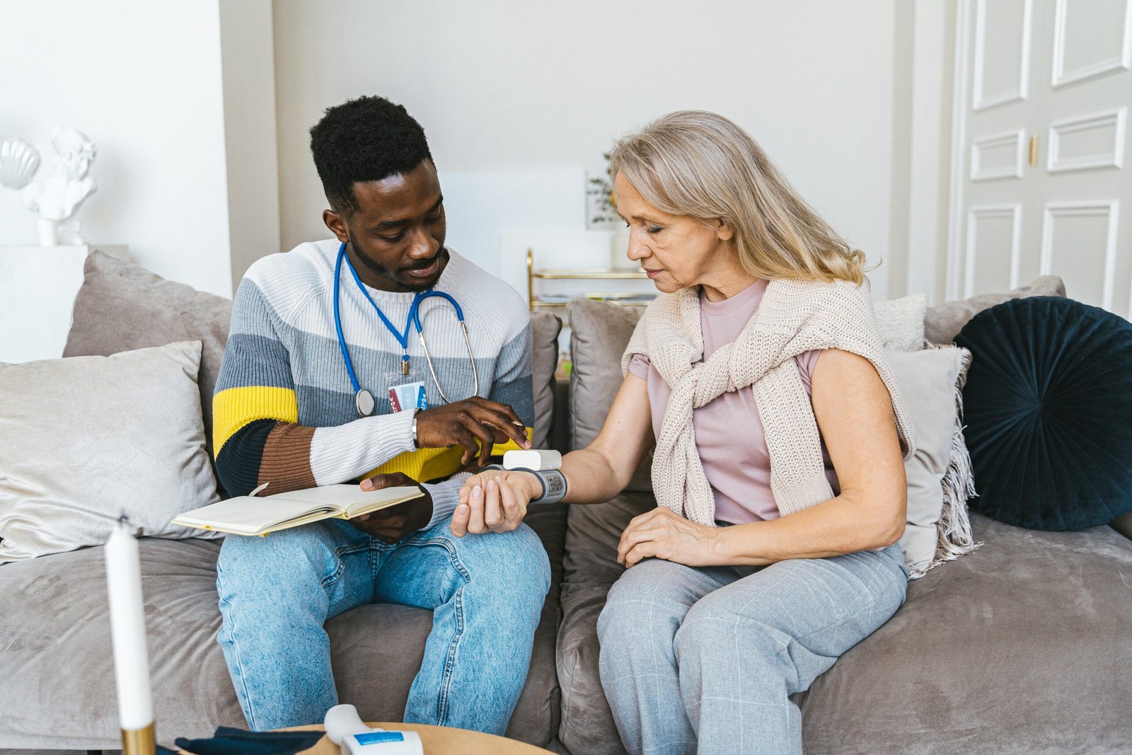 a doctor in the living room monitoring blood pressure of a lady at home