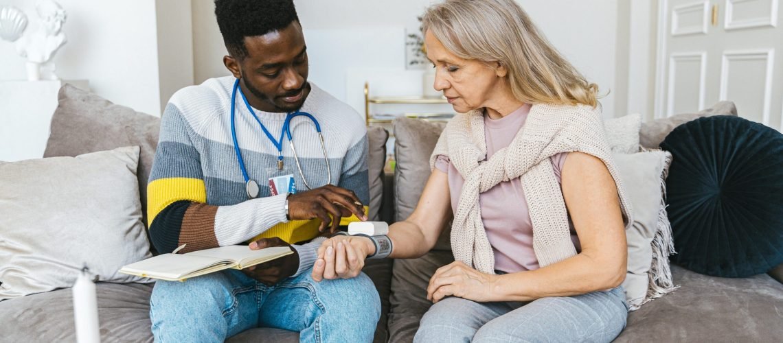 a doctor in the living room monitoring blood pressure of a lady at home