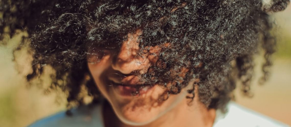 person wearing white crew-neck shirt with curly hair photo